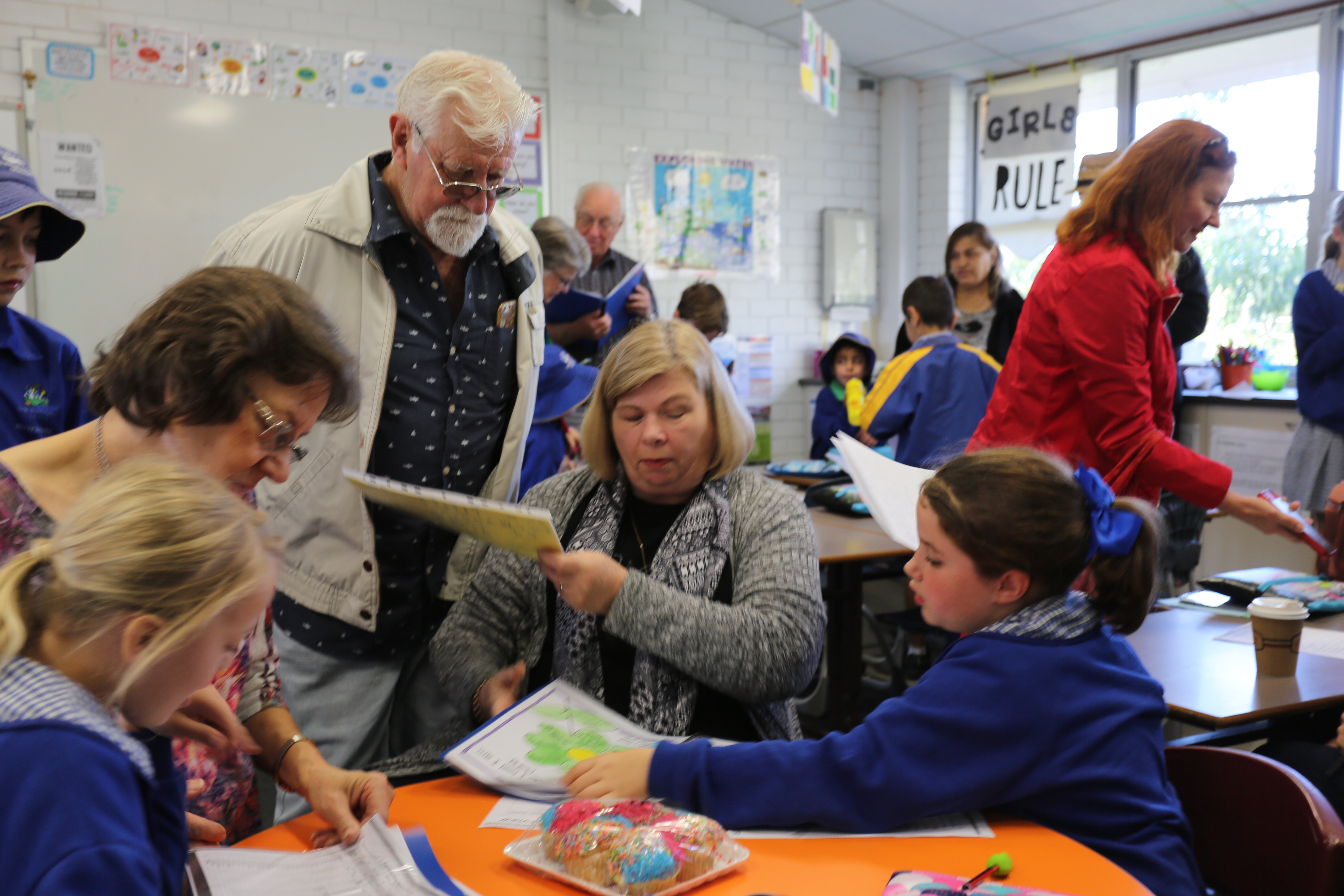 Adult volunteers working with students during a classroom learning activity.