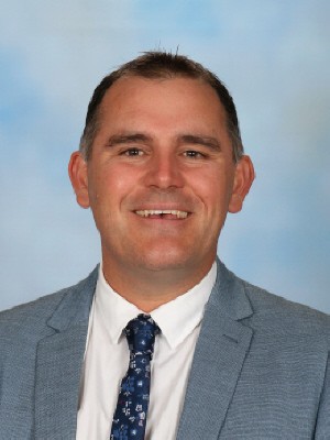Staff member portrait against a plain studio background.